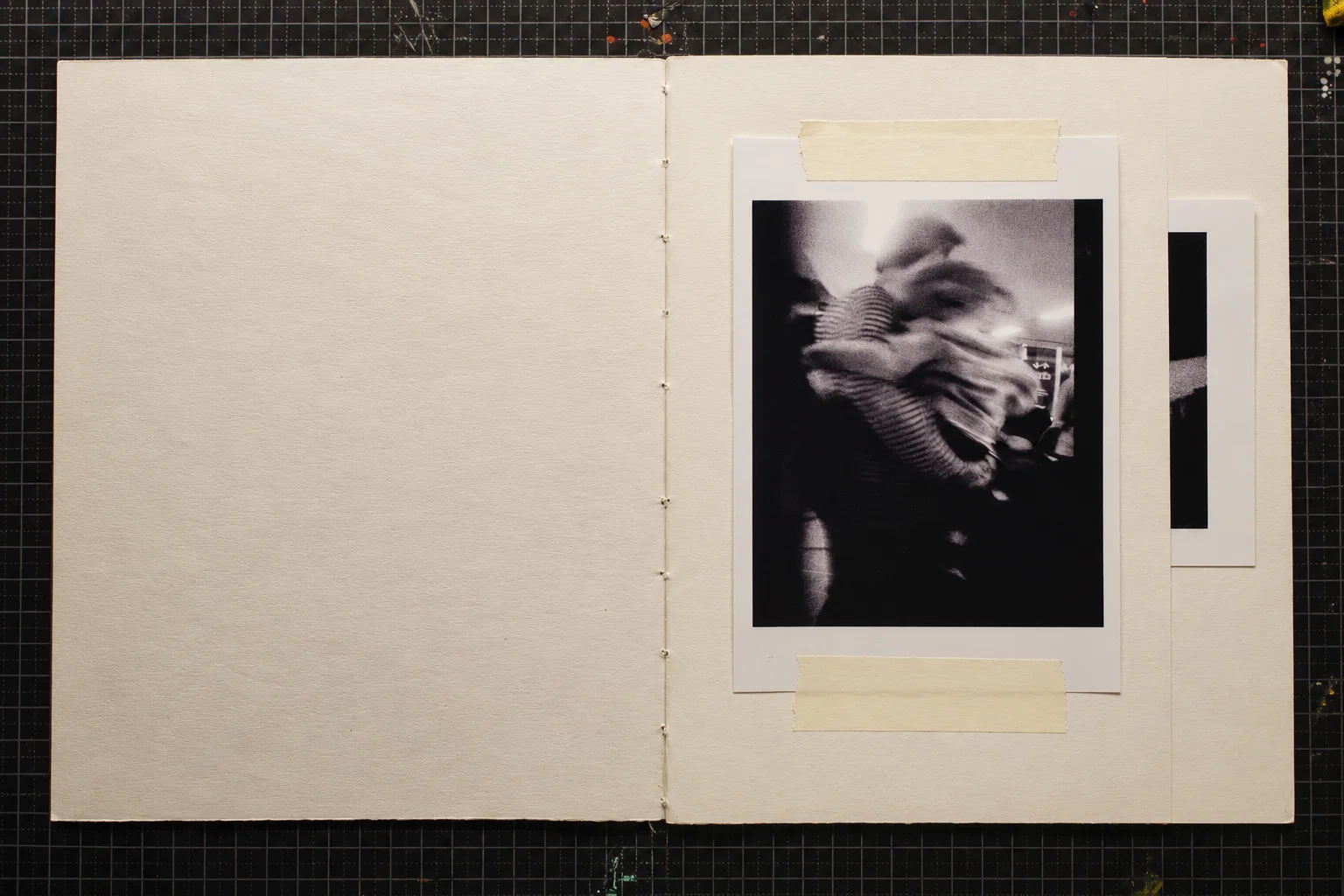 A black-and-white photograph on the right-hand page, showing blurred, overlapping figures and striped fabric. The left page is blank.
