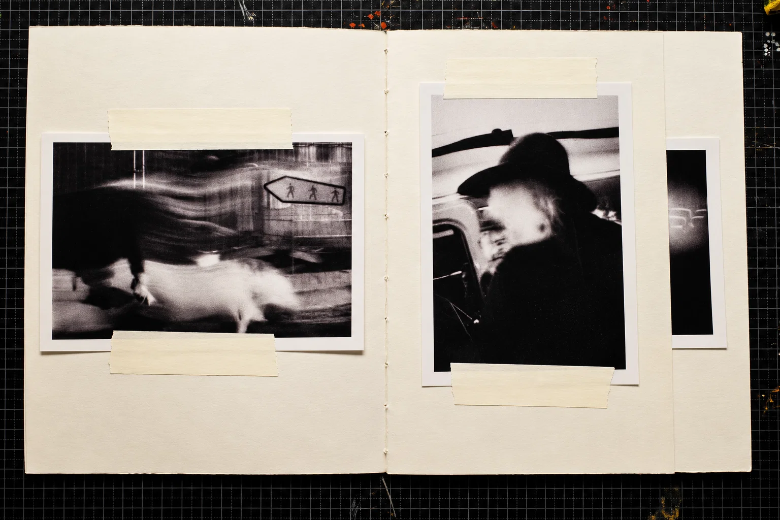 Two black-and-white photographs. On the left, blurred figures pass a tiled wall with a pedestrian direction sign. On the right, a person wearing a dark, wide-brimmed hat is photographed in profile beside a vehicle.